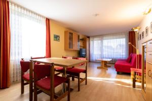 a living room with a table and red chairs at Ferienwohnpark Immenstaad am Bodensee Zwei-Zimmer-Apartment 51 07 in Immenstaad am Bodensee