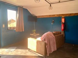 Au Cap في دربي: غرفة معيشة مع أريكة والجدار الأزرق