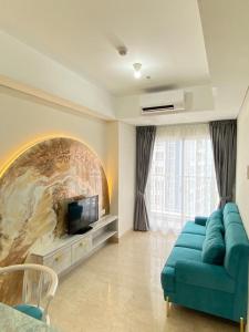 uma sala de estar com um sofá azul e uma televisão em Apartment Podomoro Medan em Medan