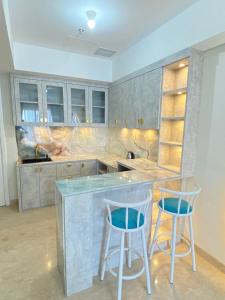 una cocina con 2 taburetes y una barra en Apartment Podomoro Medan en Medan