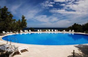 a large swimming pool with lounge chairs and the ocean at Cala Flores Sea View Apt 400m from the beach! in Porto Cervo