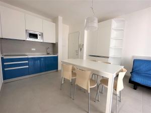 a kitchen and dining room with a white table and chairs at Residence Acapulco in Bibione