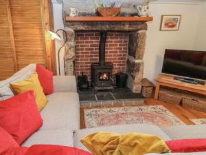 a living room with a brick fireplace and a couch at Iris Cottage in Penzance