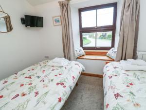 two beds in a room with a window at Iris Cottage in Penzance