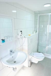 a white bathroom with a sink and a toilet at Hotel Münden in Hannoversch Münden