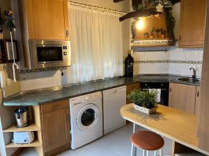 a kitchen with a washing machine and a table at Chalet Robayera a línea de playa in Miengo