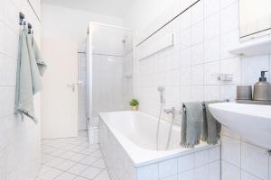 a white bathroom with a tub and a sink at Modern & Stylish for 3: Smart TV in Essen