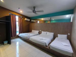 1 dormitorio con 2 camas con sábanas blancas en GOLDEN GUEST HOUSE KUANTAN en Kuantan