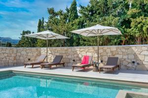 - une piscine avec 2 chaises longues et 2 parasols dans l'établissement La Serena Residence & Farm with Heated Pool, à Réthymnon