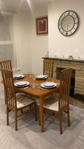 drewniany stół z 4 krzesłami i zegarem na ścianie w obiekcie Evanelly lodge w mieście Gillingham
