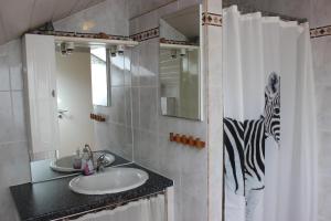 a bathroom with a sink and a zebra shower curtain at Apartment Ramersdorf in Bonn