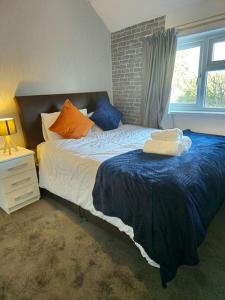 a bedroom with a bed with blue and orange pillows at Spacious Swanky Home 4 Groups & Contractors near NEC & Airport in Olton