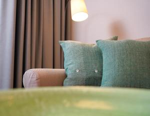 a couch with a green pillow and a lamp at Appartements "Zum Leuchtturm" Hafen Rankwitz Insel Usedom in Rankwitz