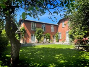 una gran casa de ladrillo rojo con un patio verde en Hotel Aahøj en Sæby