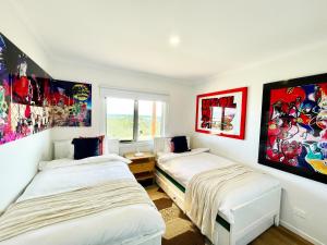 two beds in a room with paintings on the walls at If you are looking for iconic modern, look no further in San Remo