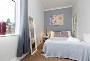 um quarto com uma cama branca e um espelho em Comfy & Homely Ideal for Families & Contractors em Darlington