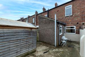 a brick building next to a garage with a chair at Comfy & Homely Ideal for Families & Contractors in Darlington