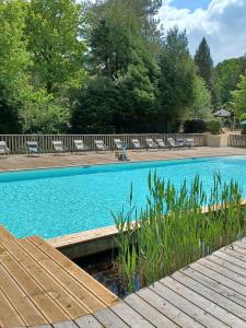 a large swimming pool with a wooden walkway next to a pool at Huttopia Rambouillet in Rambouillet