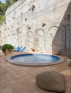 uma piscina num edifício de pedra com cadeiras e uma cadeira em Villa Puerto Beach vistas al mar em Altea