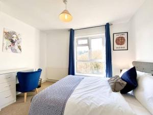 a bedroom with a bed with a blue chair and a window at Scarlet House in Batheaston