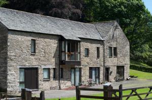 an old stone house with a balcony in a field at Grange Cottage Lakeside Windermere in Newby Bridge