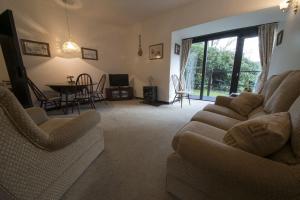 - un salon avec un canapé, une table et des chaises dans l'établissement Grange Cottage Lakeside Windermere, à Newby Bridge