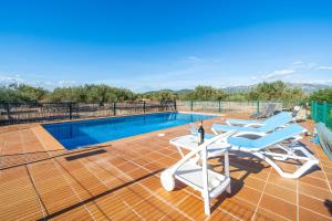 a swimming pool with chairs and a table on a deck at Hauzify I Mas Bomba in Les tres Cales