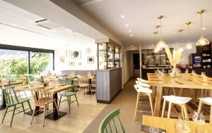 a restaurant with wooden tables and green chairs at Campanile Orange A7/ A9 in Orange