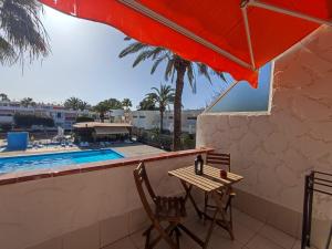 a table and chairs next to a swimming pool at Sunny terrace, fast WiFi relax & remote work quiet area in Arona