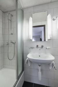 a white bathroom with a sink and a shower at Hotel Alphorn in Interlaken