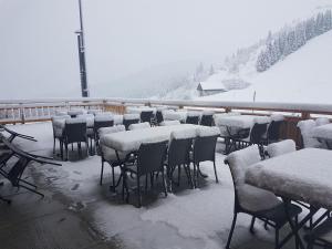 a group of tables and chairs covered in snow at Appartement Le Pic in Samoëns