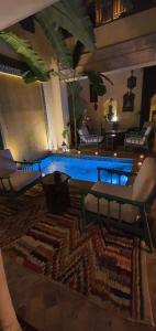 - un salon avec une table, des chaises et une piscine dans l'établissement RIAD DAR NAOMI, à Marrakech