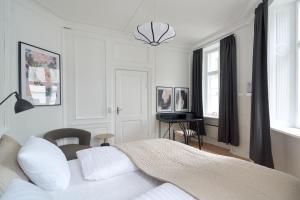 a white bedroom with a bed and a desk at Bright Apartment in the Old Town of Copenhagen in Copenhagen