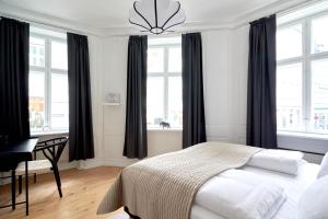 a bedroom with a bed and a desk and windows at Bright Apartment in the Old Town of Copenhagen in Copenhagen
