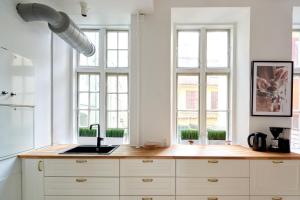 a kitchen with white cabinets and a sink and windows at Bright Apartment in the Old Town of Copenhagen in Copenhagen