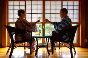 Ein Mann und eine Frau sitzen an einem Tisch mit Weingläsern in der Unterkunft Ryosou Makibanoie 18 years or older in Yufu