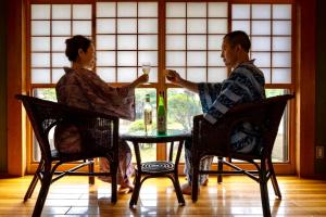 un homme et une femme assis à une table avec des verres à vin dans l'établissement Ryosou Makibanoie 18 years or older, à Yufu