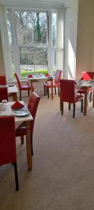 jadalnia ze stołami, krzesłami i oknami w obiekcie Tirionfa Guest House w mieście Criccieth