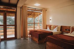 een slaapkamer met 2 bedden en een groot raam bij Ollie resort in Ella