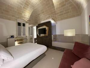 a bedroom with a bed and a tv and a couch at Euvodia Luxury Rooms in Matera