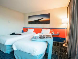 una camera d'albergo con due letti e un tavolo di ibis Styles Marseille Aéroport a Vitrolles