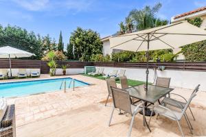 a table with an umbrella next to a swimming pool at Villa Sunnyside Mandali by Ezoria Villas in Protaras