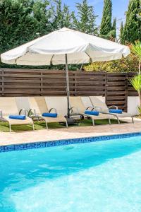 an umbrella and chairs next to a swimming pool at Villa Sunnyside Mandali by Ezoria Villas in Protaras