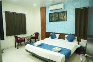 a hotel room with a bed and a table and chairs at Hotel Avon International in Aurangabad