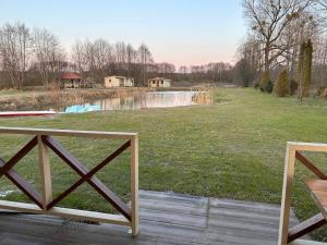 a view of a park with a pond and houses at Domek nad stawem - Mazury in Rozogi