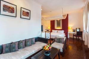 um quarto de hotel com um sofá e uma cama em Angsana Maison Souvannaphoum Hotel em Luang Prabang