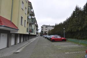 un'auto rossa parcheggiata in un parcheggio accanto agli edifici di WROCLOVE_NET MUCHOBOR a Breslavia