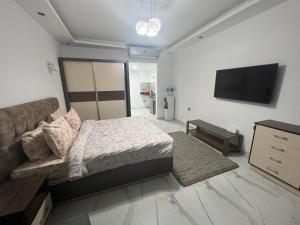 ein Schlafzimmer mit einem Bett und einem Sofa sowie einem Flachbild-TV in der Unterkunft Luxury Apartment Panorama Naama Heights Resort in Sharm El Sheikh