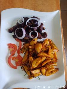 a white plate of food with fries and onions at Comfort Guest House in Kericho