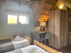 a bedroom with two beds and a desk and a window at Ingwe Bush Lodge in Hoedspruit